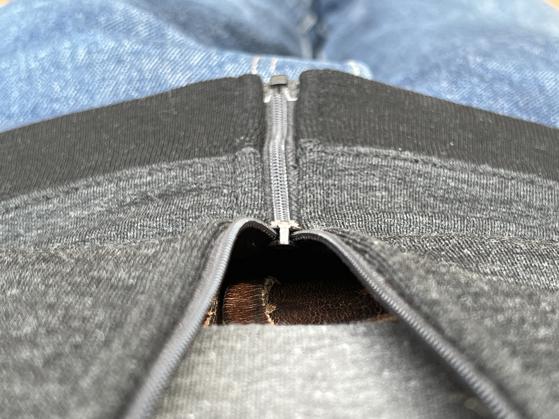 a zippered sweatshirt, shown from the wearers perspective, with zipper pull in close-up at center
